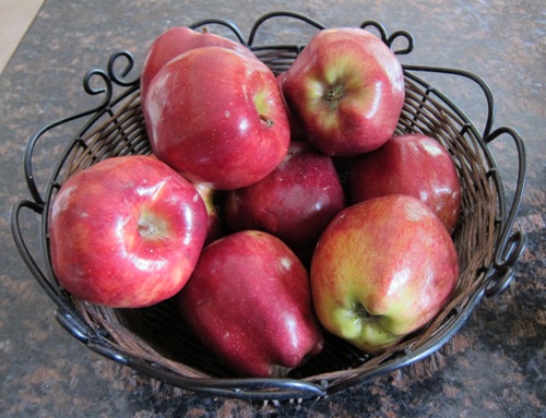 red apples stored in a basket on the counter